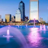 Cover photo of the Best Things to do in Jacksonville FL (perfect for first time visitors) showing a lake with multiple lit up fountains in front of the city sykline
