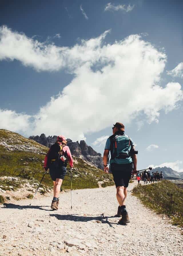 Couple of hikers with trekking poles walking behind a group of hikers