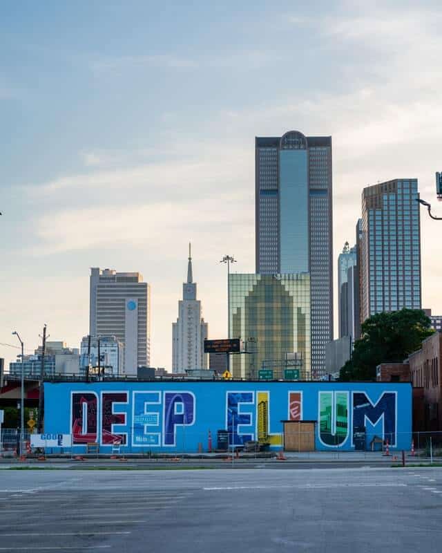 Deep Ellum mural on a wall in fornt of the Dallas Skyline