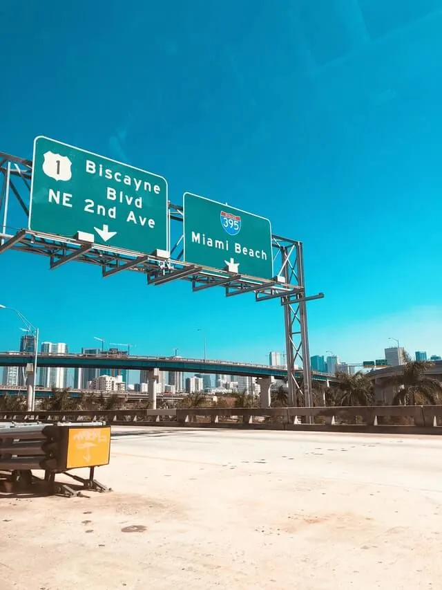 Freeway signs above an empty highway showing directions to Miami Beach