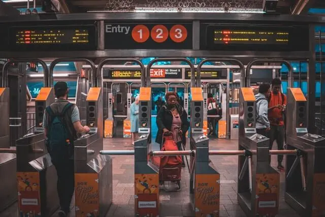 New York Subway Turnstiles with Subway car in the background and platform indicator board above