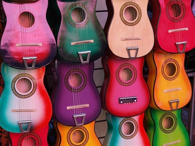 Multicoloured guitars hangin on display at a market stall