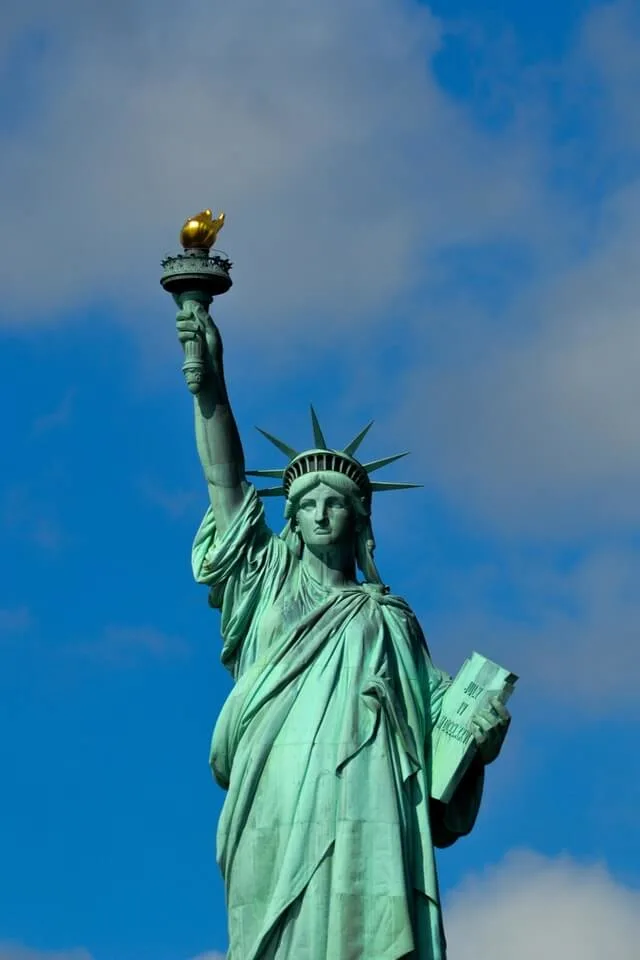 Statue of Liberty New York City with a blue sky behind her green structure