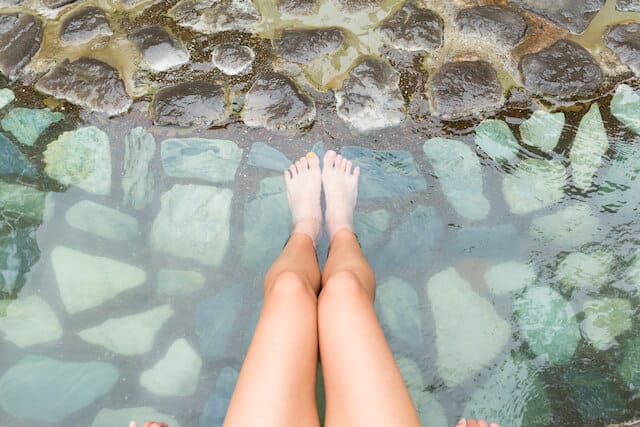 Womans legs in the shallow clear water of a hot spring pool 