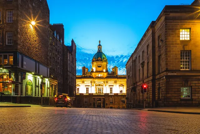 Museum on the mound lit up at night viewed between two buildings on the Royal Mile