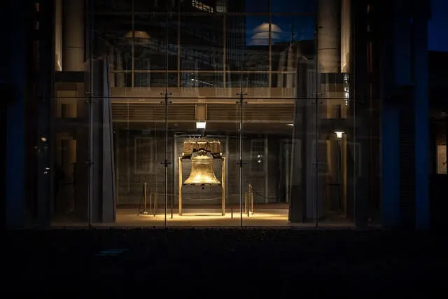 Liberty Bell lit up at night behind a glass wall in Philadelphia