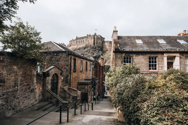 Vennel Steps leading down between two stone buildings with Edinburgh Castle on the hill in the background