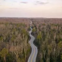 Incredible Wisconsin Road Trips cover image of a paved road winding through a wooden area taken from above