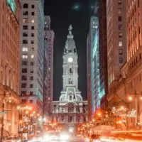 Reasons to Visit Philadelphia cover photo looking down North Broad Street to City Hall, the large while building lit up in the distance with light trails on each side of the street