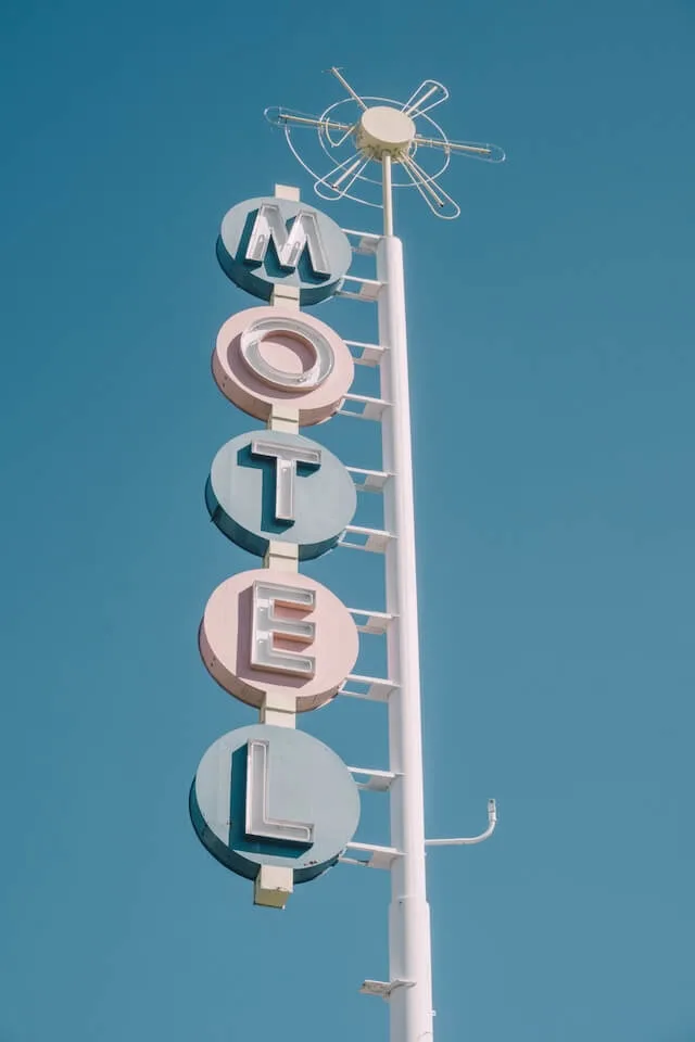 Vertical Motel Sign with alternating blue and pink individual letters attached to a white pole