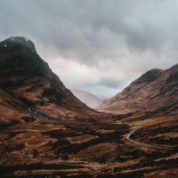 Best Road Trips in Europe cover photo of a road winding through the brown moody mountains of Scotland