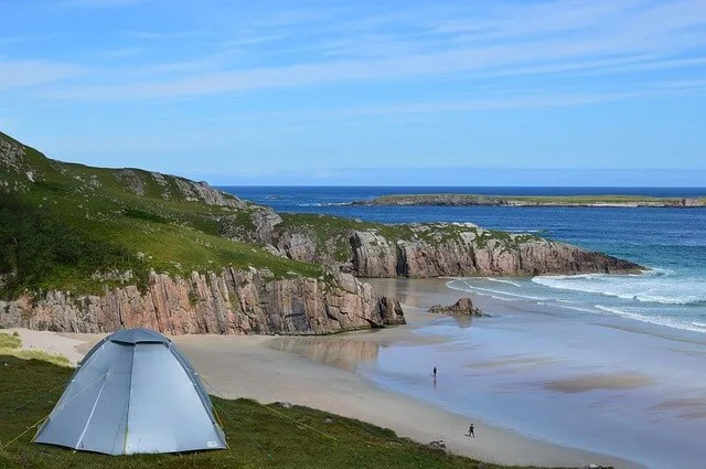 NC 500 Road trip - tent on a hillside overlooking a beach with the tide out