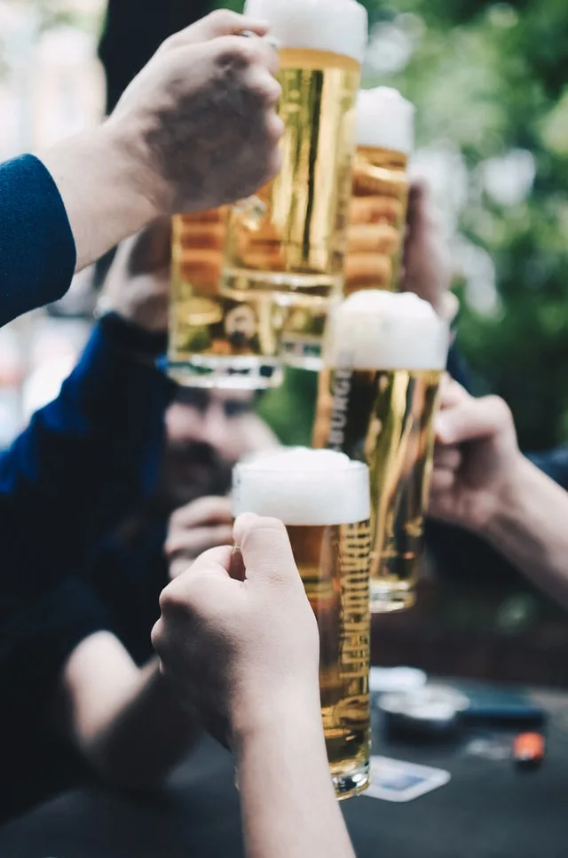 Multiple people cheersing large beers