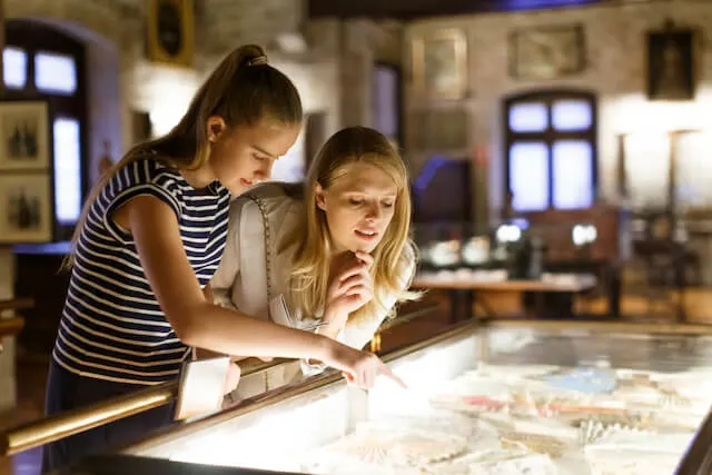 Two women standing over an exhibit in a museum