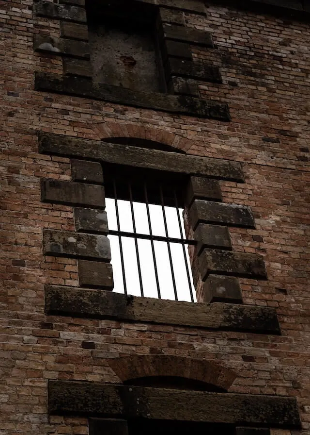 Old brick building with bars across the now glassless windows