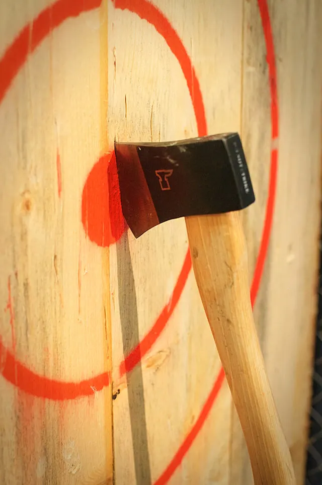 Axe lodged into the red center of a target pained on light wood