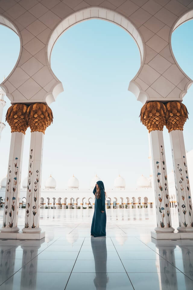 Woman wearing a burka and covering her head inside a while open air mosque