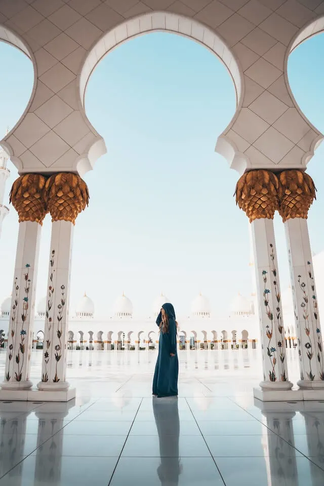 Woman wearing a burka and covering her head inside a while open air mosque