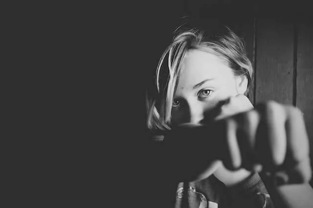 Woman with short hair arm outstretched towards the camera as if punching