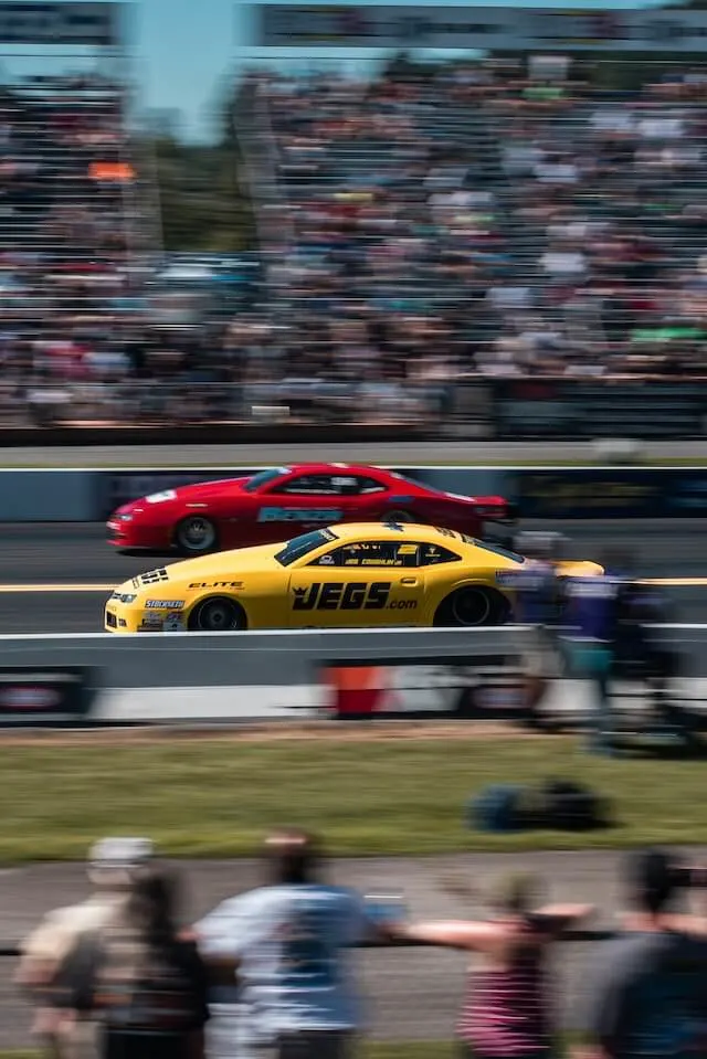 Red and Yellow Car Drag Racing at high speed in front of a crowd of people