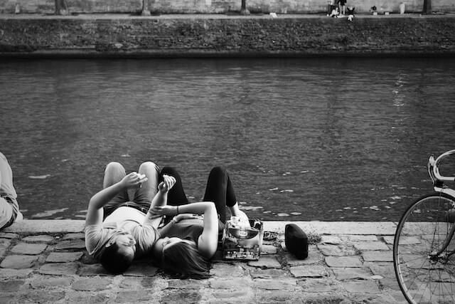 Couple lay down next to each other on the banks of the River Seine
