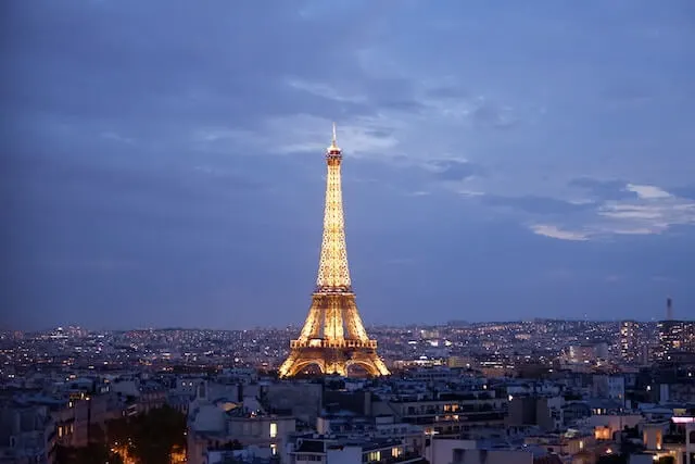 Eiffel Tower lit up at night surrounded by a dusky blue sky