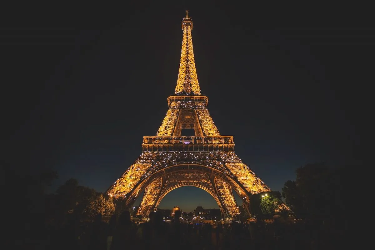 Famous Paris Landmarks cover photo of the Eiffel Tower lit up at night against a pitch black sky