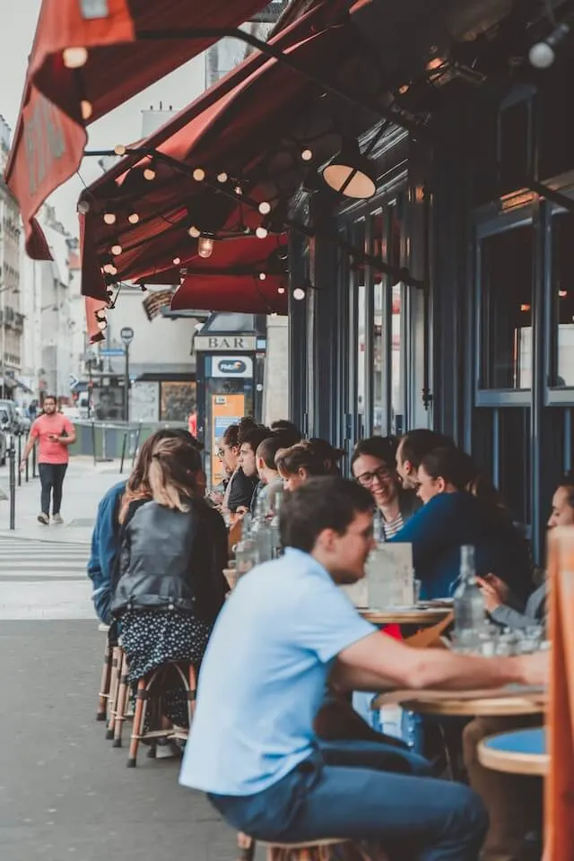Groups of young people stat at tables and chairs outside a cafe in Paris