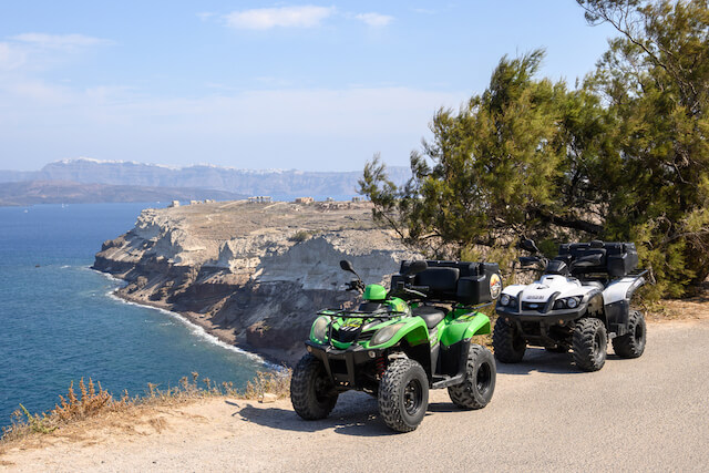 Two quad bikes parked on the rugged coastline of Santorini