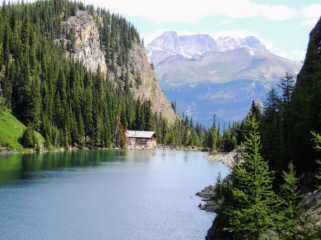 Agnes Lake Teahouse on the edge of a lake surrounded by trees with a mountain in the background