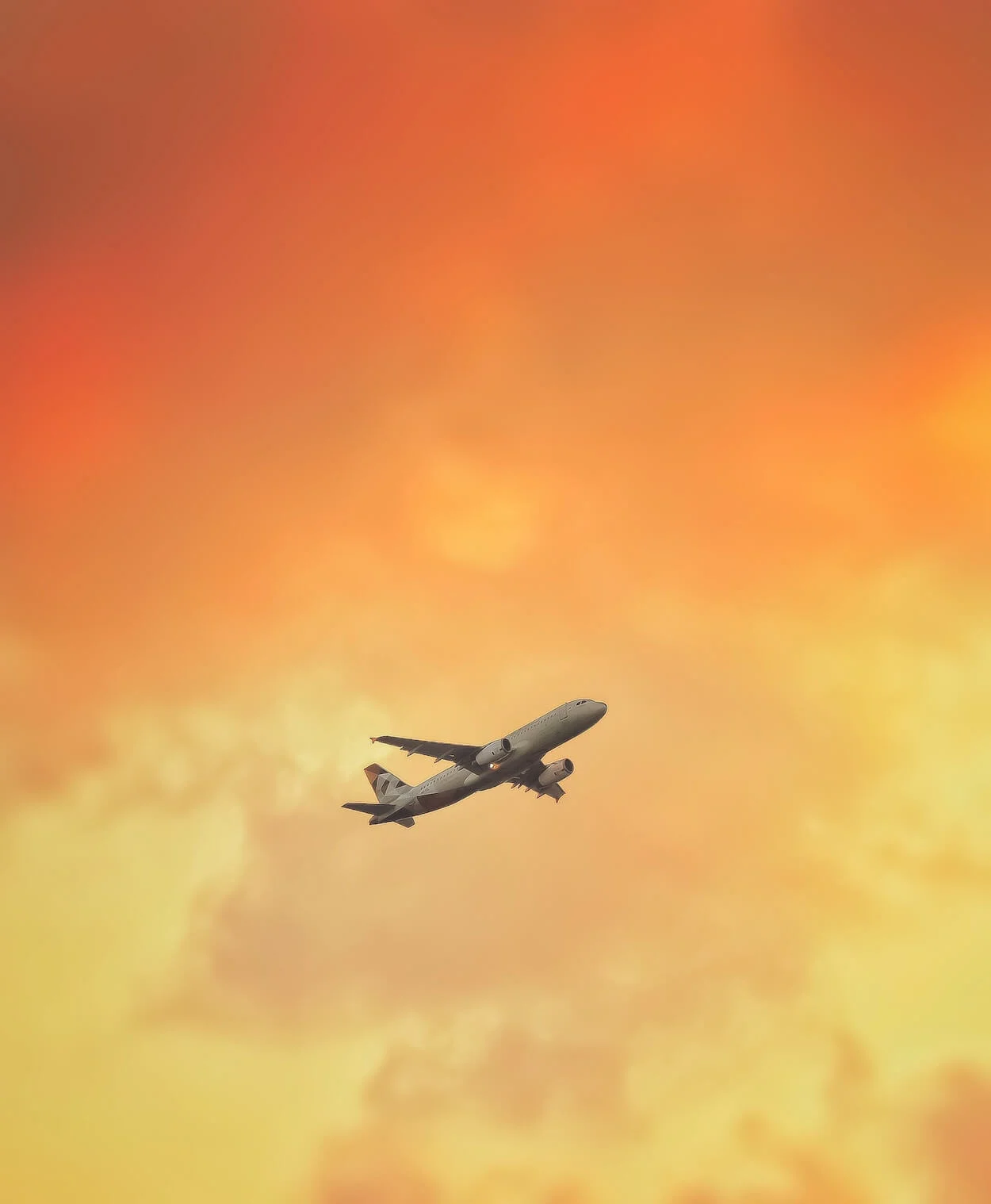 Essential Tips for Long Flights final image of a plane flying in the sky surrounded by a orange and yellow sunset sky
