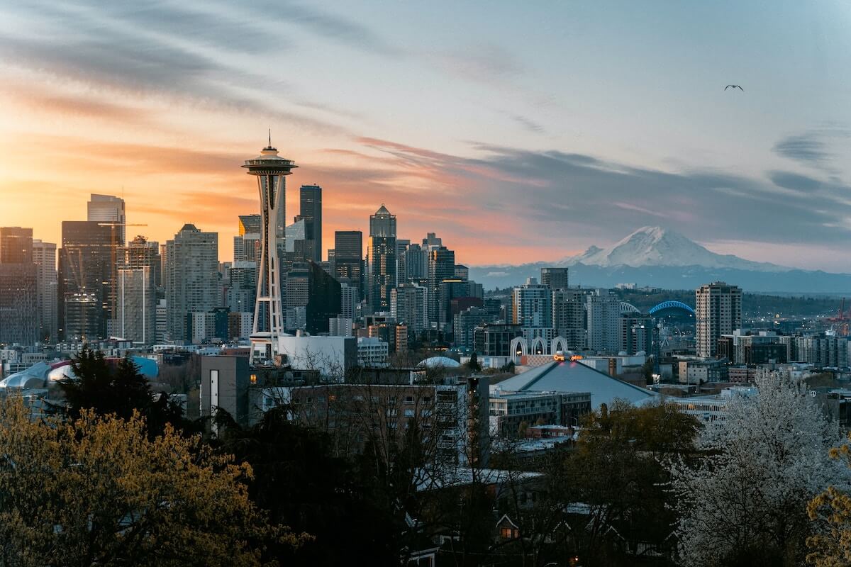 One Day in Seattle Itinerary cover photo of the Seattle skyline, with prominent Space Needle as the sun sets in the distance