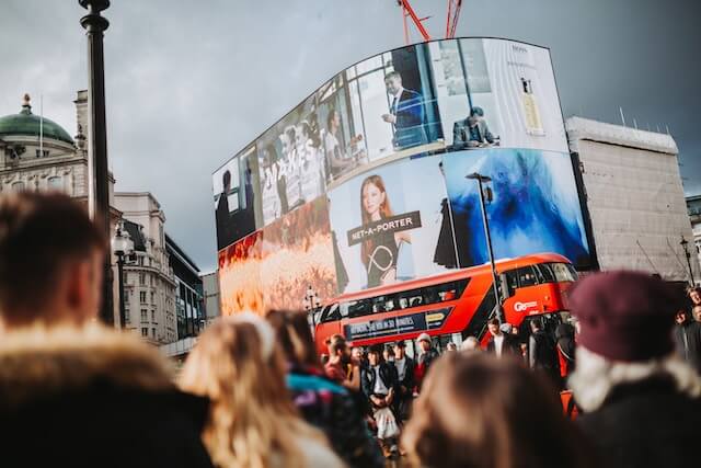 Tourists in front of the large screens at Oxford Circus in London