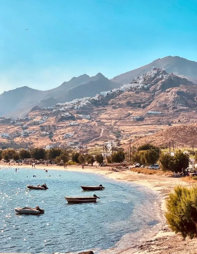 View of Chora from the curved sand beach, small fishing boats anchored just off shore