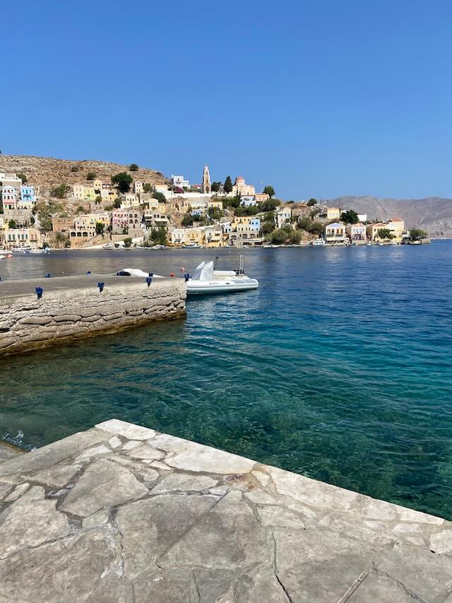 Port area of Symi island in Greece with azure blue water along the coastline