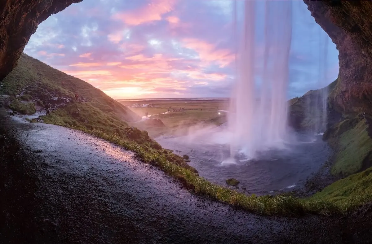 3 Days in Iceland Itinerary cover image taken from behind a waterfall at sunset