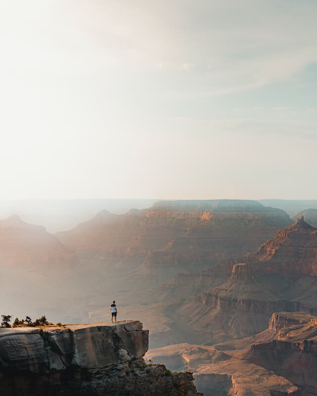 Man standing on a ledge looking out into the Grand Canyon