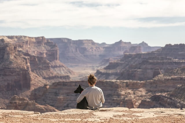 Woman with her arm around a black dog on the rim of the Grand Canyon