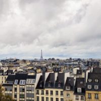 Facts about Paris cover photo of traditional Parisian slate rooftops, with the Eiffel tower standing above them in the distance