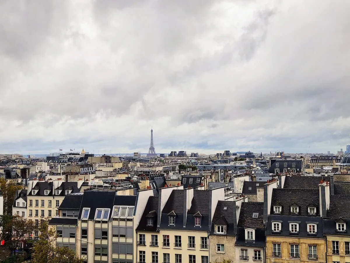 Facts about Paris cover photo of traditional Parisian slate rooftops, with the Eiffel tower standing above them in the distance